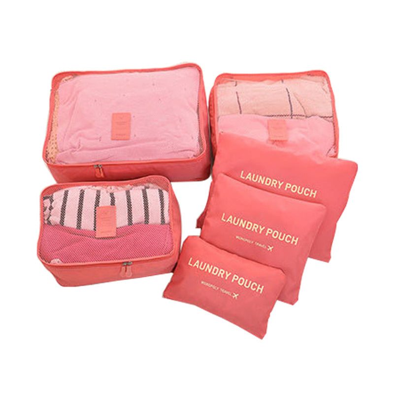 Zesdelige roze reisorganizer-set met drie packing cubes en drie waszakken voor kleding in de koffer.
