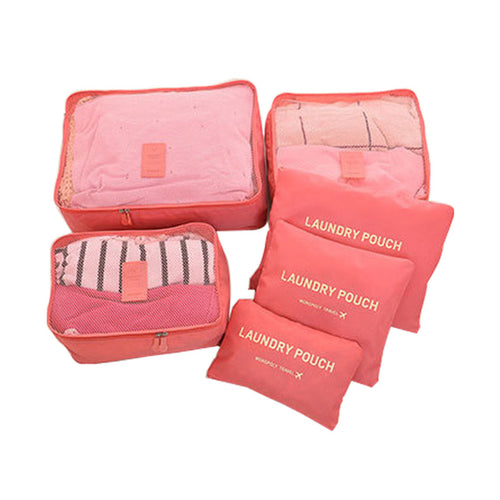 Zesdelige roze reisorganizer-set met drie packing cubes en drie waszakken voor kleding in de koffer.